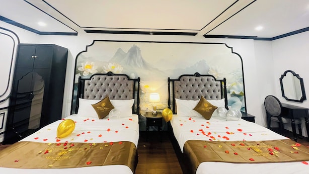 A hotel room with two beds, a mural on the wall, a desk with a chair, and a wardrobe. - Vera Luxury Hotel (Hanoi)