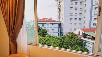 Una habitación con vistas a un edificio, una mesa con una botella y vasos, y dos sillas.