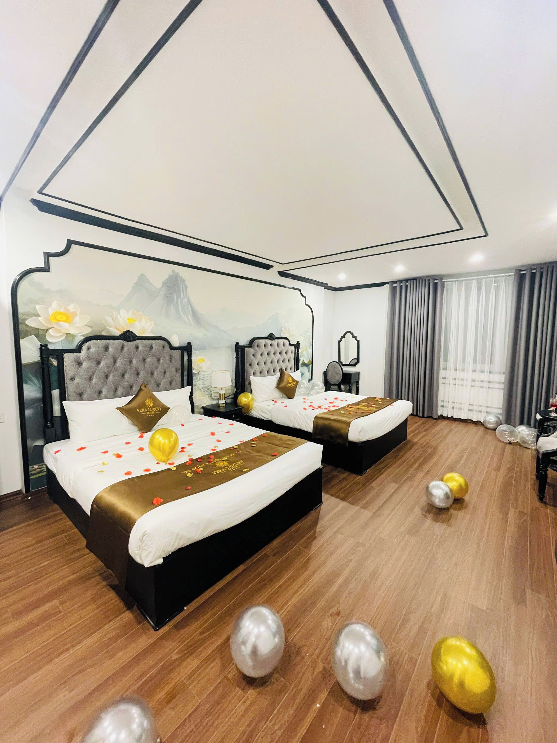 A hotel room with two beds, a decorative wall mural, and a wooden floor.
