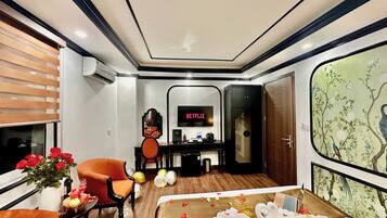 A hotel room with a bed, a desk, a chair, a TV, and a large window.