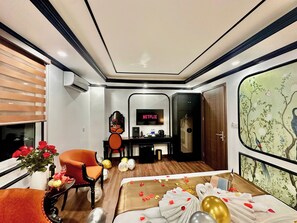 Una habitación de hotel con cama, escritorio, silla, televisión y un ventanal grande.
