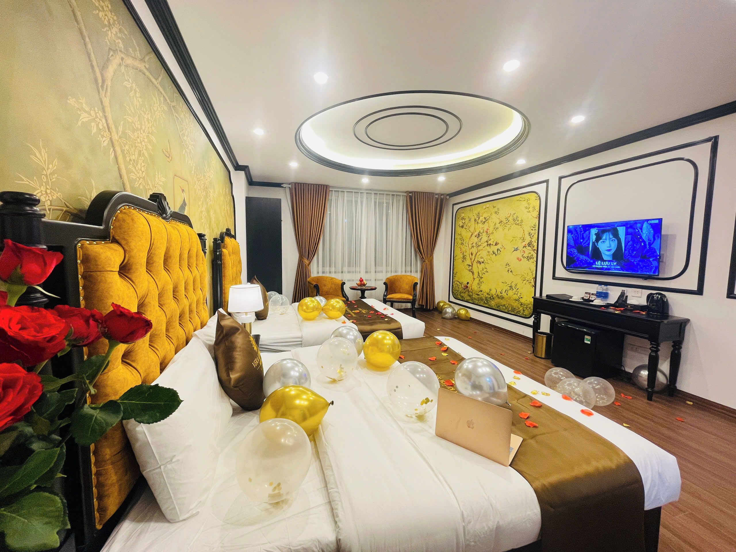 A hotel room with a bed, a television, and a desk with a laptop.