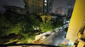 A nighttime view from a balcony overlooking a street with parked cars and buildings in the background. - Vera Luxury Hotel (Hanoi)