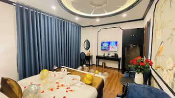 A hotel room with a bed, a desk, a TV, and a blue chair.