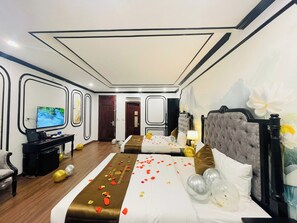 Una habitació d'hotel amb un llit, una taula de treball, una televisió i una porta que dona a una altra habitació.