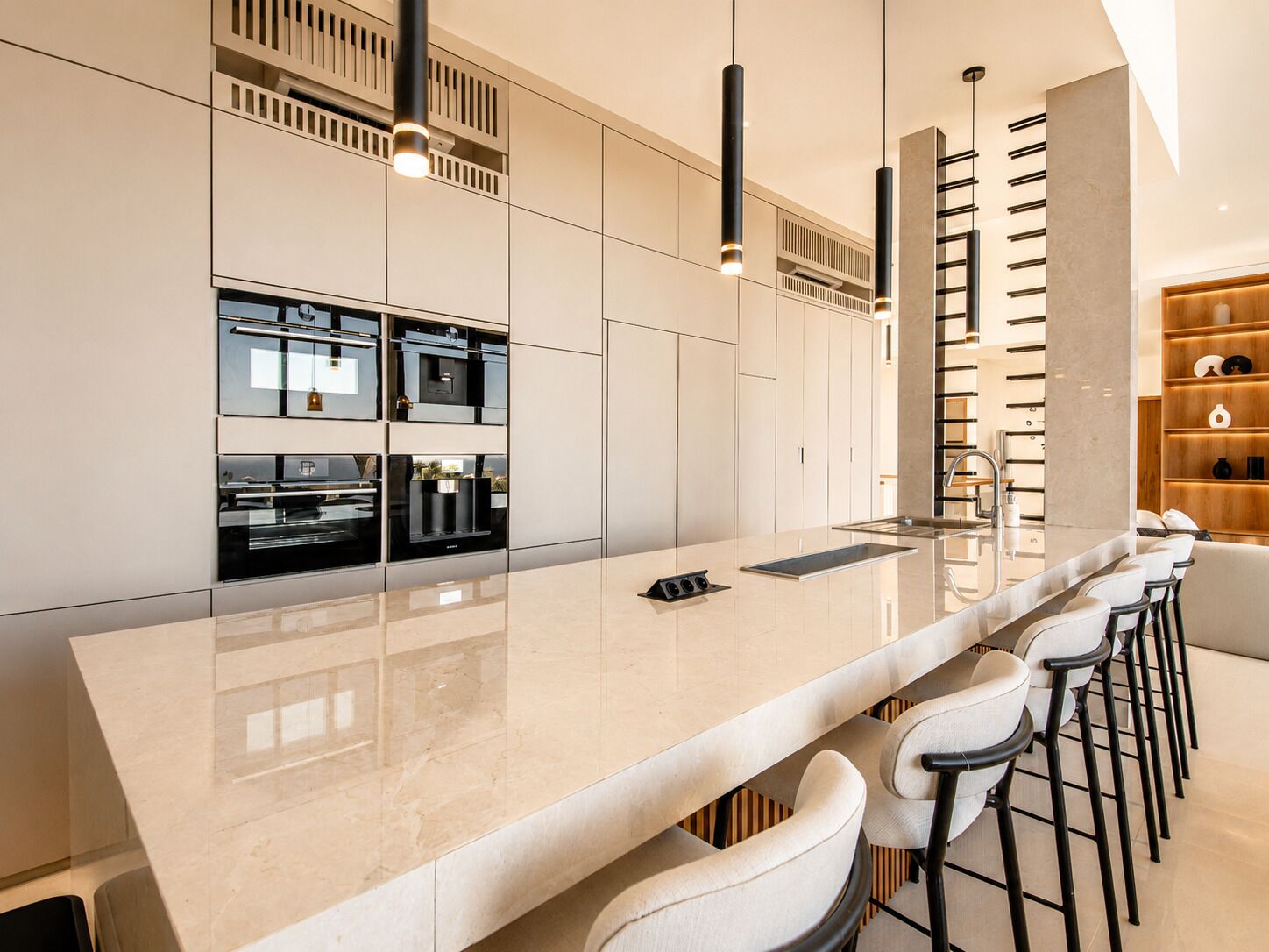 A modern kitchen with a large island, built-in appliances, and a bar area with stools.