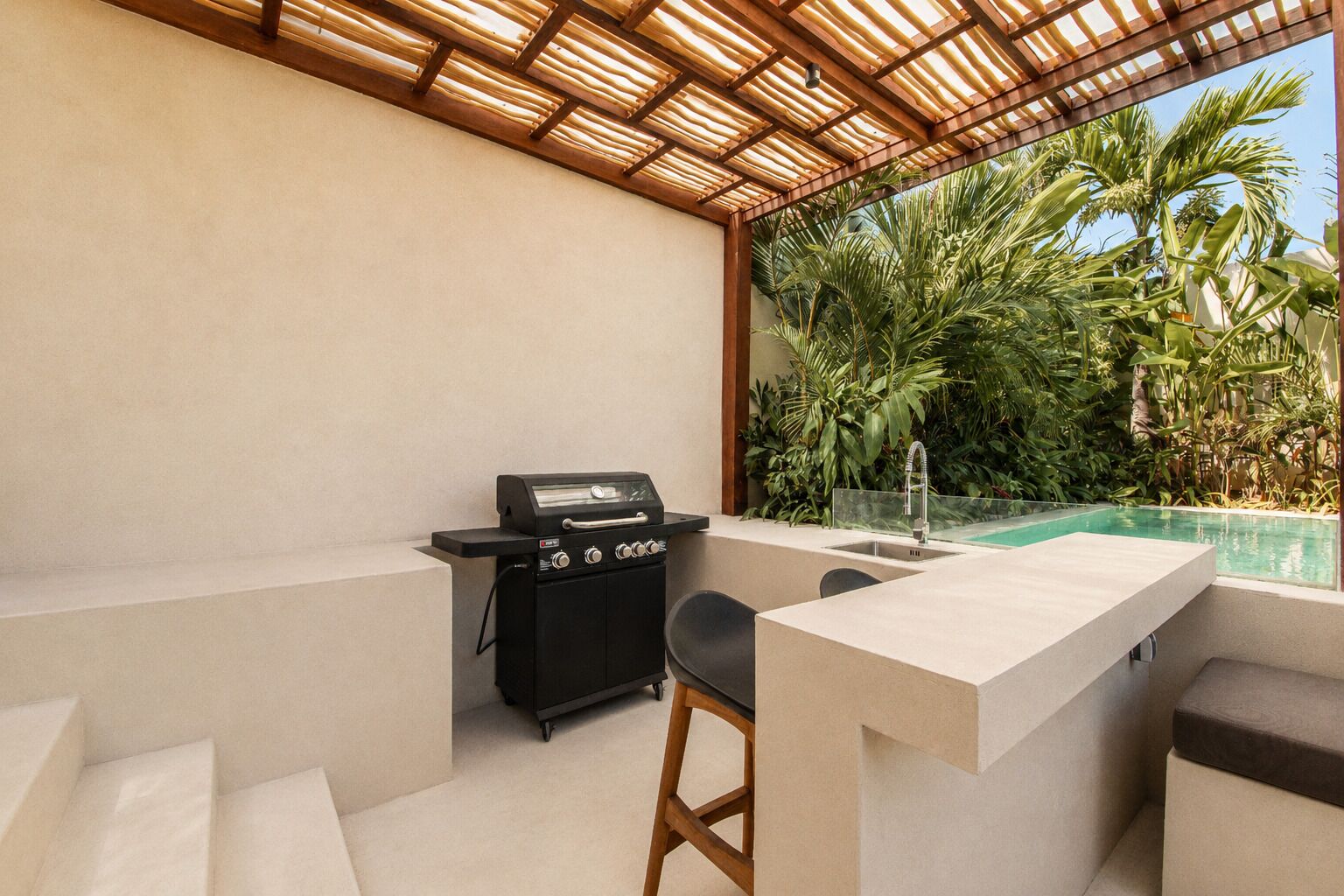 Une terrasse extérieure équipée d’un barbecue, d’une piscine et d’un espace salon.