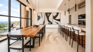 Un espace repas moderne avec une longue table en bois, des chaises noires et des œuvres d’art abstraites accrochées au mur.