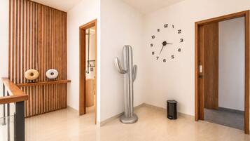 Un interior moderno con un revestimiento de listones de madera, una escultura de cactus, un reloj de pared y un cubo de basura.