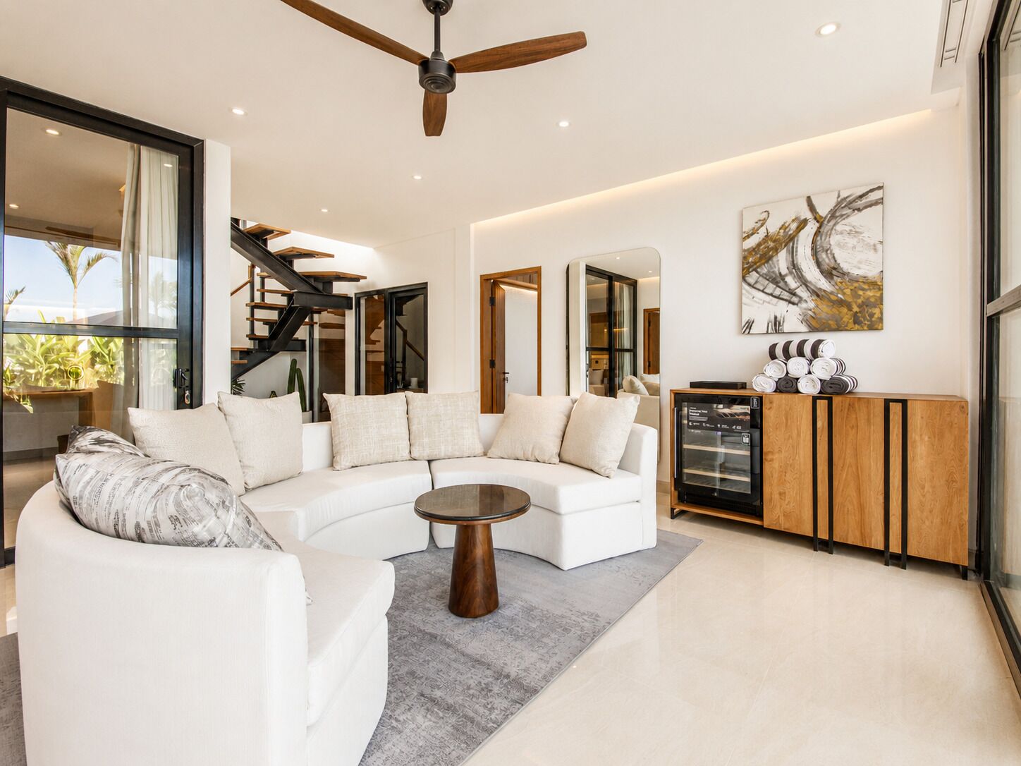 A modern living room with a white sofa, a coffee table, and a ceiling fan.
