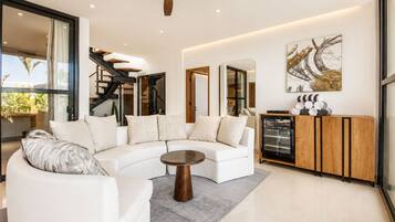 A modern living room with a white sofa, a coffee table, and a ceiling fan.