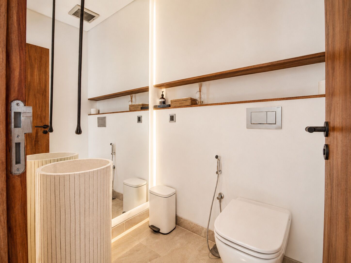 A modern bathroom with a toilet, bidet, and vanity with a mirror.