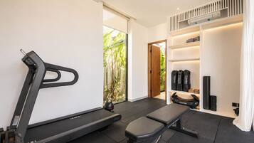 Un gimnasio moderno para el hogar con cinta de correr, banco y estanterías.