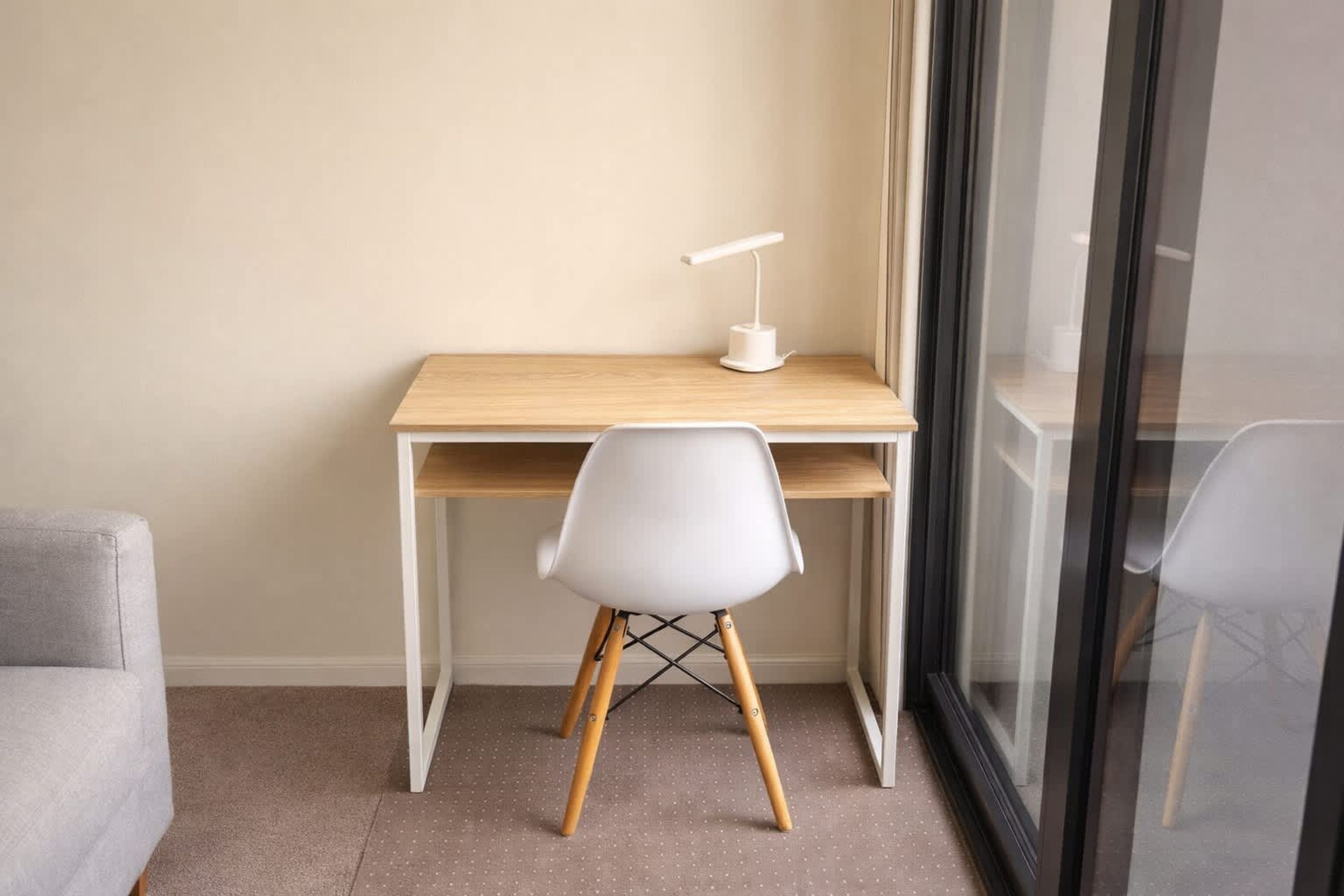Un espacio de trabajo pequeño y ordenado, con un escritorio, una silla y una lámpara de escritorio.