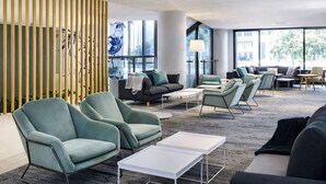 Ein stilvoller Lounge-Bereich mit Sitzgelegenheiten, Tischen und großen Fenstern.