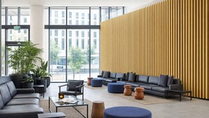 Eine moderne Lobby mit Ledersofas, einem Glastisch, Topfpflanzen und einem großen Fenster mit Blick auf die Stadt.