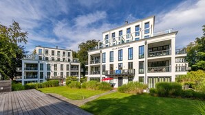 Et moderne hotel med flere altaner og en velplejet have.