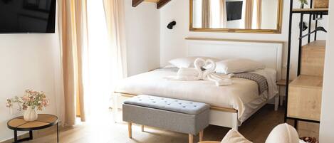 Un dormitorio con techo inclinado, una cama con cabecera, una mesita de noche, una silla y un reloj en la pared.