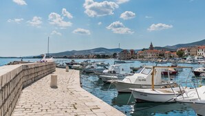 A marina with boats docked, a stone wall, and buildings in the background. - Studio apartment Milica  (Kaštel Novi)