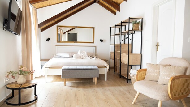 A bedroom with a bed, a bench, a chair, a TV, a mirror, and a shelf with plants. - Studio apartment Milica  (Kaštel Novi)