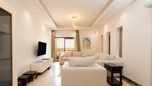 Ein modernes Wohnzimmer mit Flachbildfernseher, einer Couch, einem Couchtisch und einem TV-Schrank.