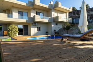 Une maison moderne à deux étages dotée d’une piscine, d’une terrasse en bois et de mobilier d’extérieur.