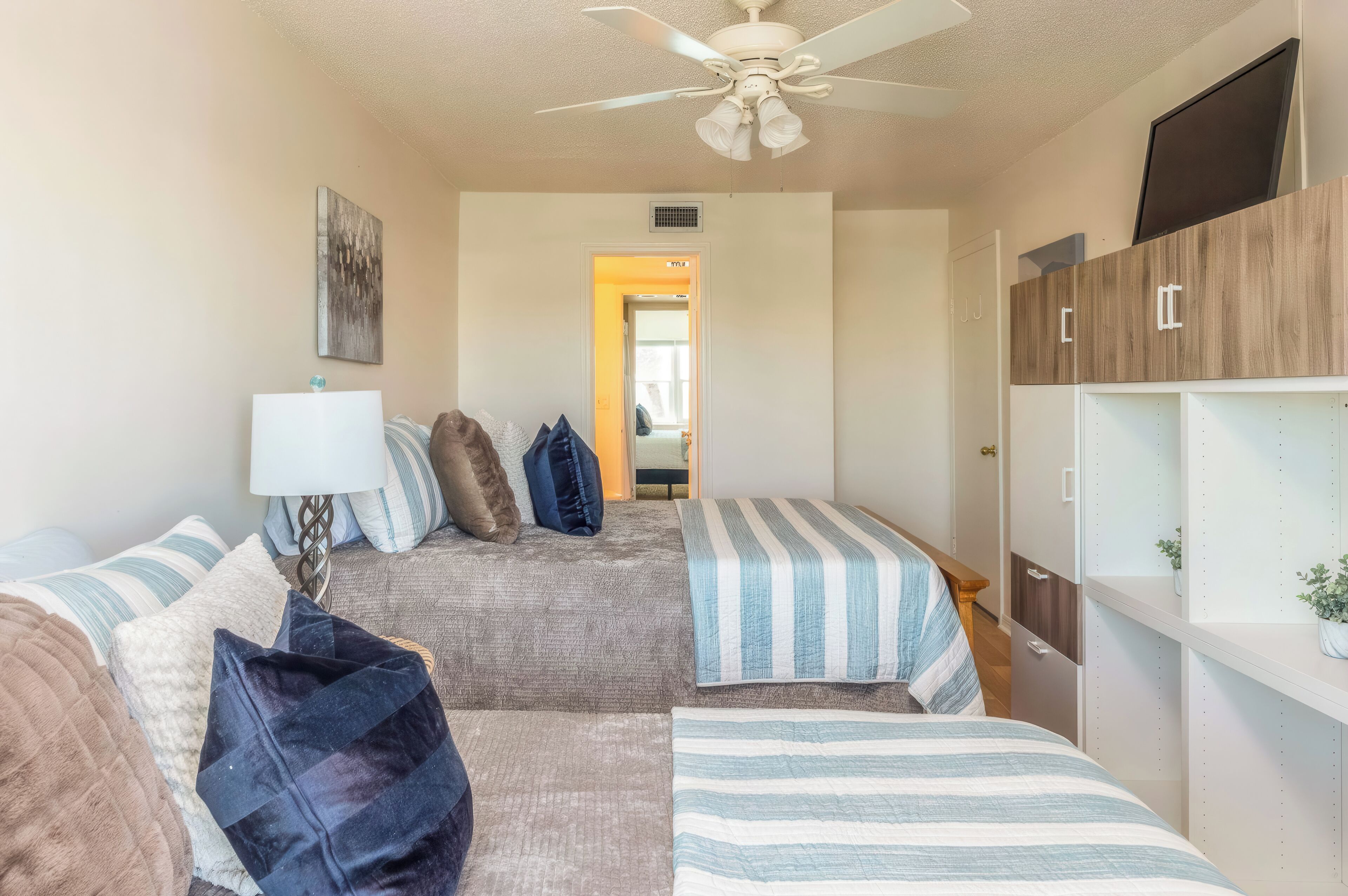 A bedroom with a bed, a nightstand, a lamp, a ceiling fan, and a wardrobe.