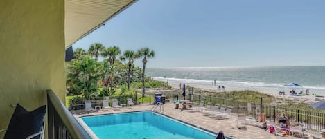 Ein Pool mit Blick auf den Strand, Liegestühle und Sonnenschirme.
