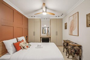 Ein Hotelzimmer mit einem großen Bett, einem Deckenventilator, einem Kamin und einem kleinen Tisch mit einem gemusterten Tischläufer.