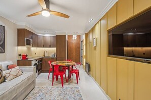 Ein kompakter Wohnbereich mit Essplatz, Küchenzeile und Deckenventilator.
