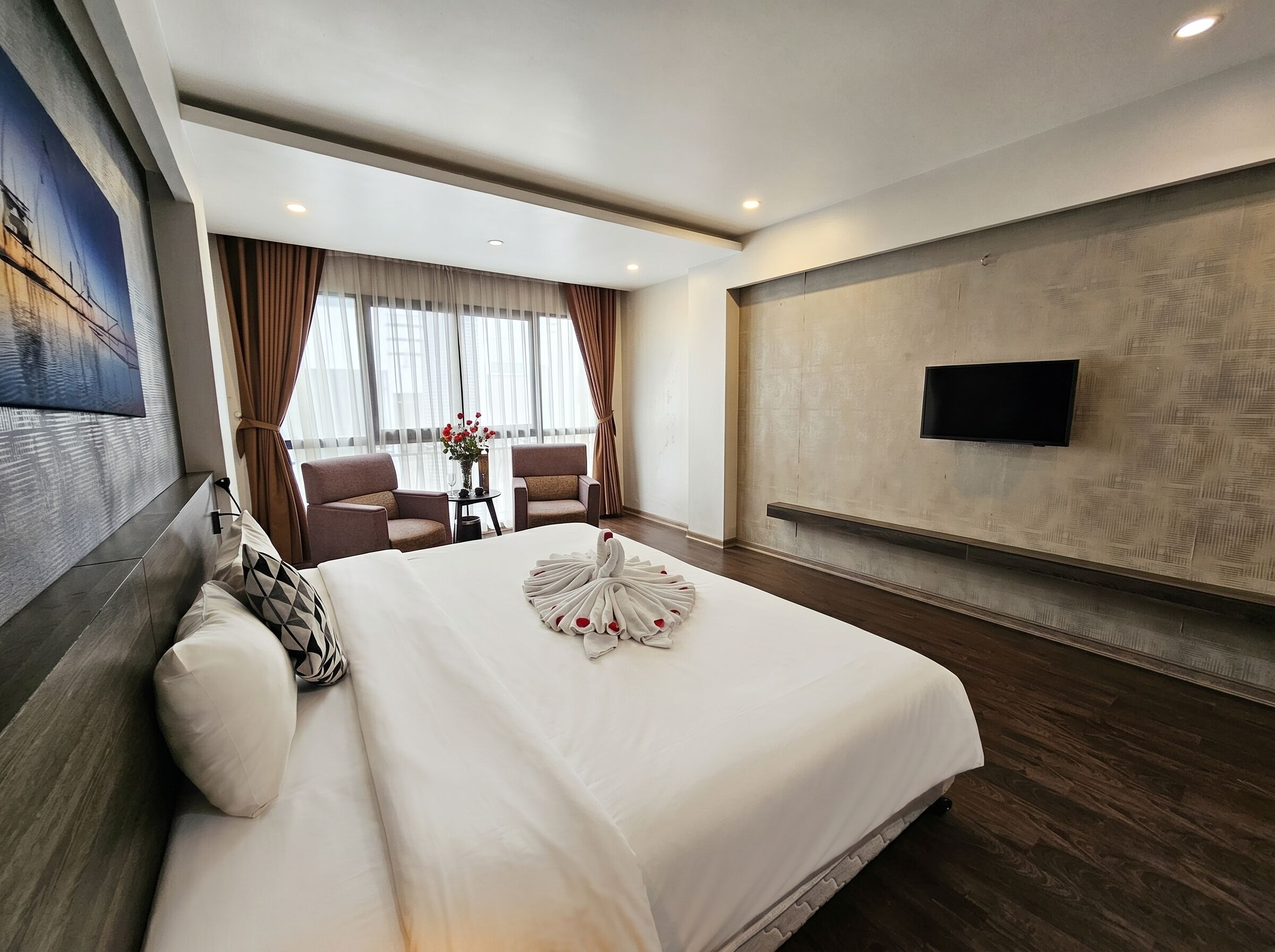 Une chambre d’hôtel avec un grand lit, un téléviseur à écran plat fixé au mur et une vue sur l’extérieur par la fenêtre.