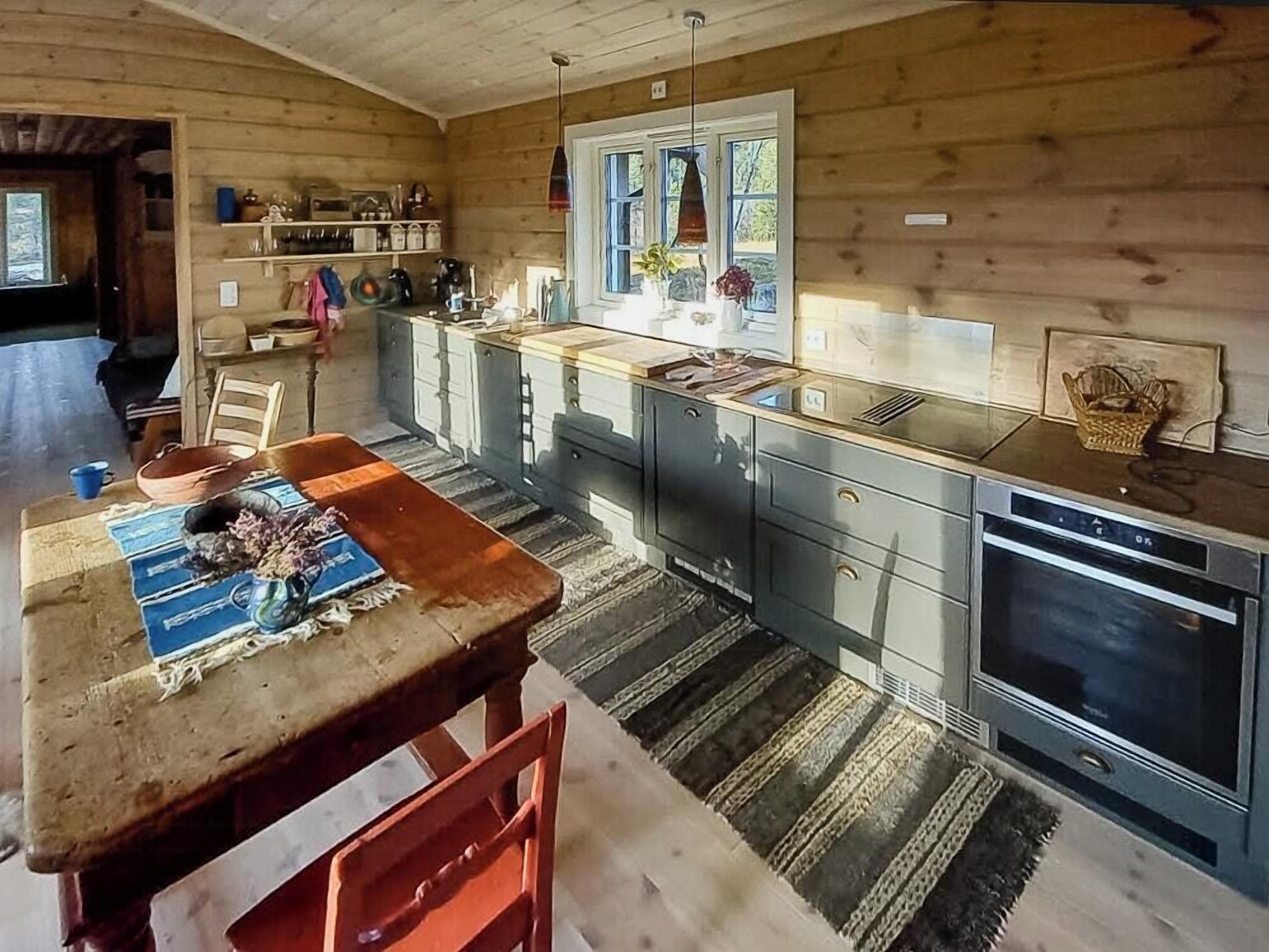 A wooden cabin interior with a kitchen area, dining table, and chairs.