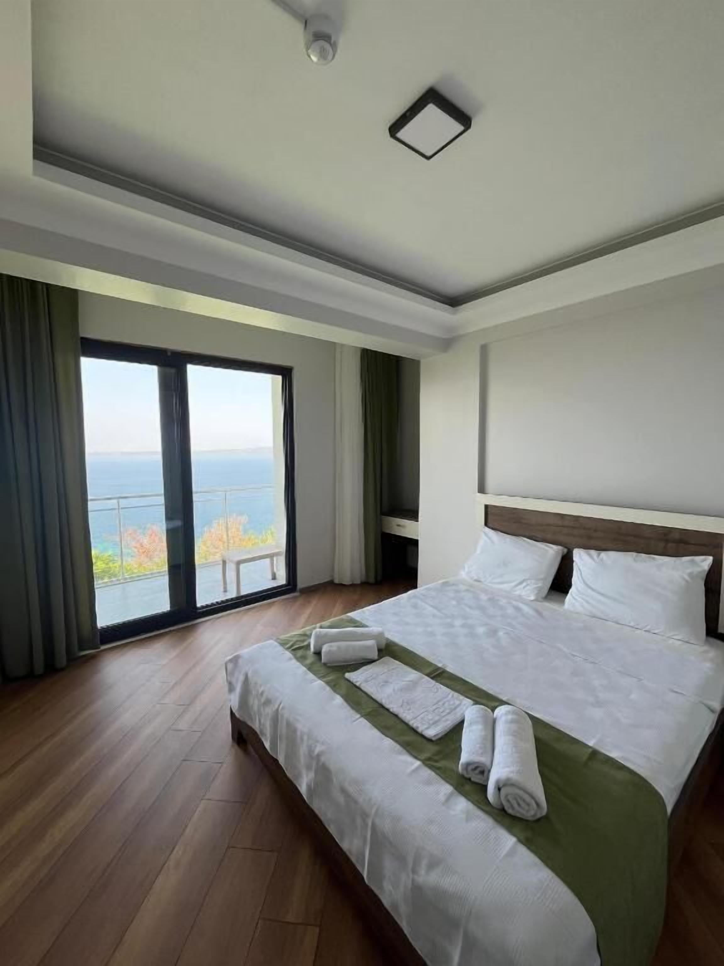 A hotel room with a large bed, a view of the ocean, and a balcony.