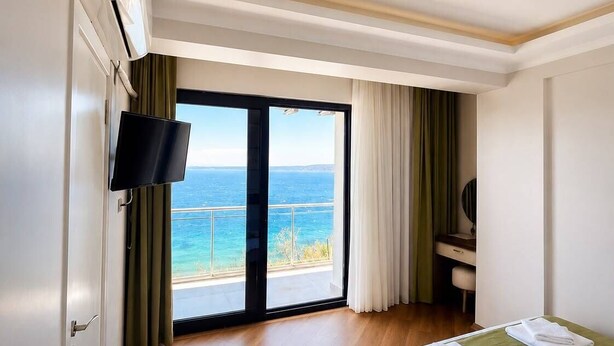 A hotel room with a large window, a bed, a flat-screen TV, and a ceiling-mounted light fixture.