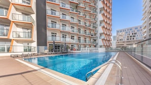 A swimming pool with a tiled deck, surrounded by multi-story buildings with balconies. - Free Housekeeping Visits During Your Stay - Stayshort - Stylish 1 Bed Apartment in Al Jaddaf for 2 With Pool Gym (Dubai)