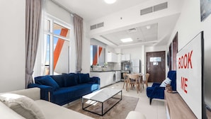 A modern living room with a sofa, coffee table, and a TV. - Free Housekeeping Visits During Your Stay - Stayshort - Stylish 1 Bed Apartment in Al Jaddaf for 2 With Pool Gym (Dubai)