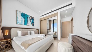 A modern hotel room with a large bed, a desk, a mirror, and a painting on the wall. - Free Housekeeping Visits During Your Stay - Stayshort - 1BR in Jumeirah Village Circle Sleeps 4 With Balcony (Dubai)