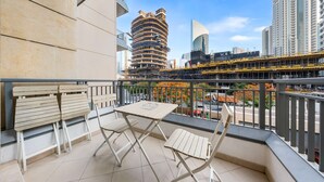 A balcony with a table and chairs, a view of a cityscape with modern buildings, and a clear sky. - Free Housekeeping Visits During Your Stay - Stayshort - Modern Studio That Sleeps 4 in Downtown (Dubai)