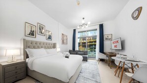 A modern bedroom with a bed, bedside table, and a desk with chairs. - Free Housekeeping Visits During Your Stay - Stayshort - Modern Studio That Sleeps 4 in Downtown (Dubai)