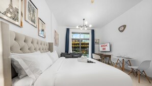 A modern hotel room with a large bed, a desk, and a view of the city. - Free Housekeeping Visits During Your Stay - Stayshort - Modern Studio That Sleeps 4 in Downtown (Dubai)