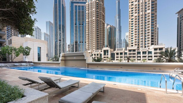 A rooftop pool with lounge chairs and a view of high-rise buildings. - Free Housekeeping Visits During Your Stay - Stayshort - Modern Studio That Sleeps 4 in Downtown (Dubai)