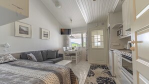 Ein Schlafzimmer mit einem Bett, einem Sofa, einem Schreibtisch und einer Küchenzeile mit Mikrowelle und Backofen.