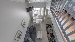 Ein modernes Interieur mit einem grauen Sofa, einem Esstisch für zwei Personen und einer Treppe mit Geländer.