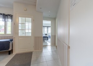 A hallway with a door leading to a bedroom, a radiator, and a window with curtains. - Levistar 912 | 2BR | Sauna | Steps to Shops & Ski (Kittilä)