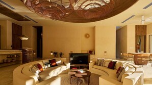 A modern living room with a curved sofa, a coffee table, and a TV. - Luxury 7BR Villa With Private Pool in Cap Cana (Punta Cana)