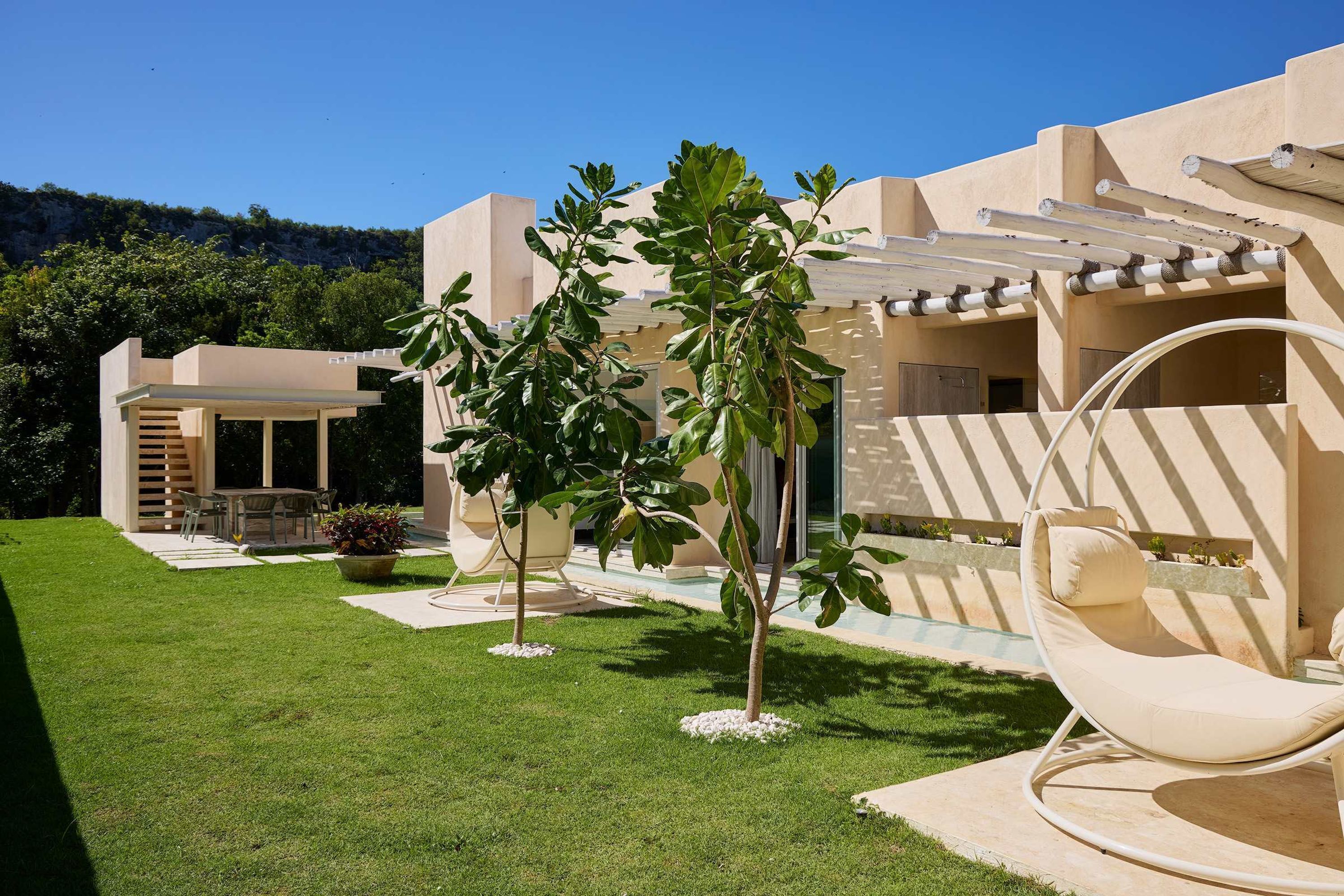 A modern outdoor seating area with a cushioned chair, a small table, and a pergola structure.