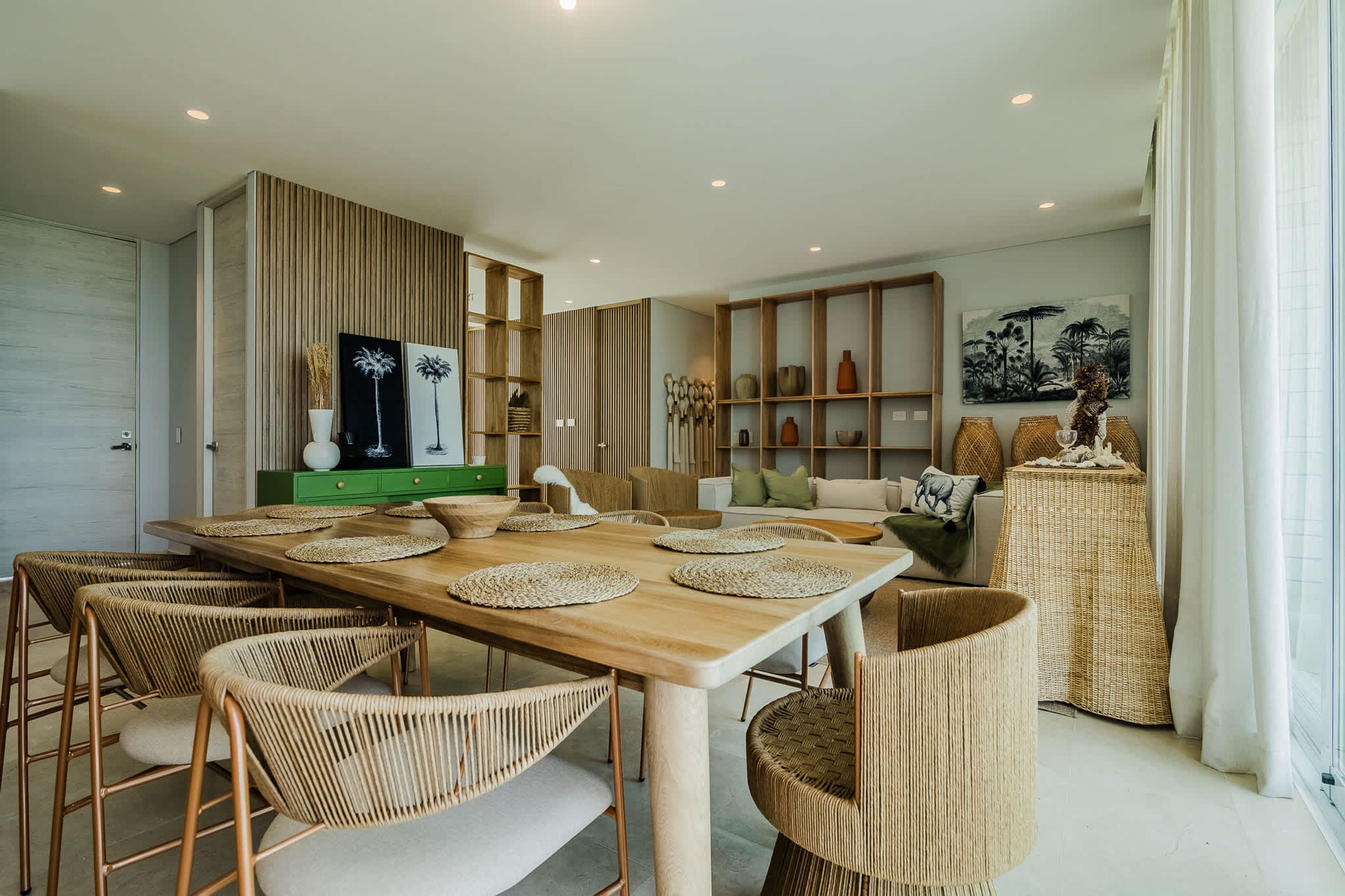 A modern dining area with a wooden table, woven chairs, and a green cabinet.