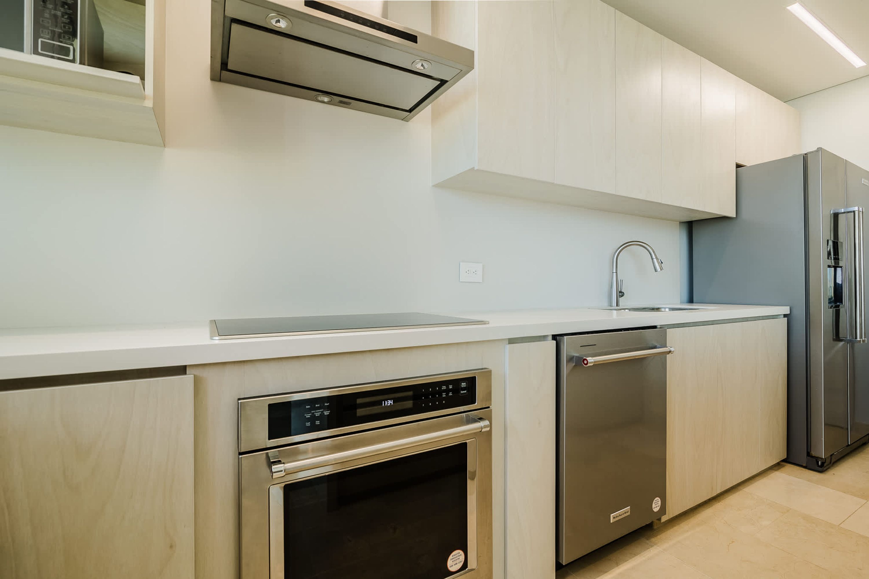 A modern kitchen with stainless steel appliances, a dishwasher, and light-colored cabinetry.