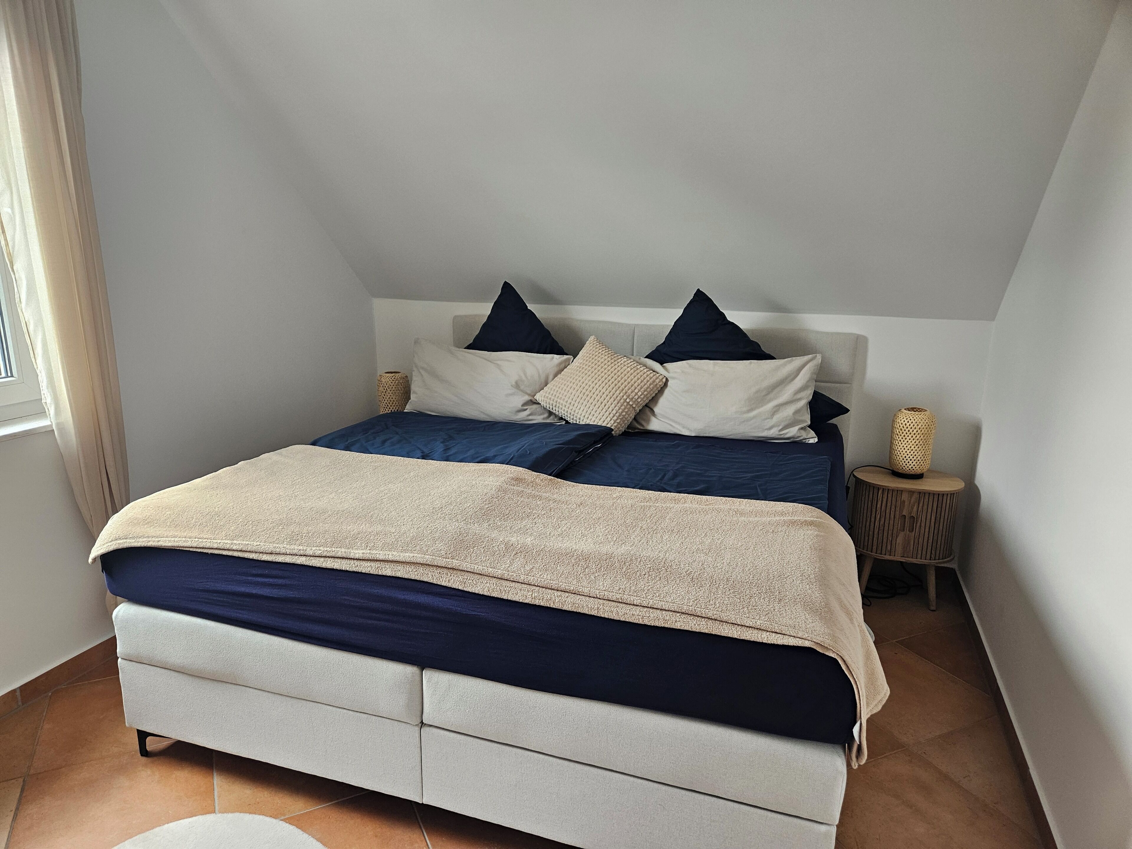 Ein Schlafzimmer mit Bett, Kissen, Nachttisch und Lampe.