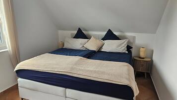 Ein Schlafzimmer mit Bett, Kissen, Nachttisch und Lampe.